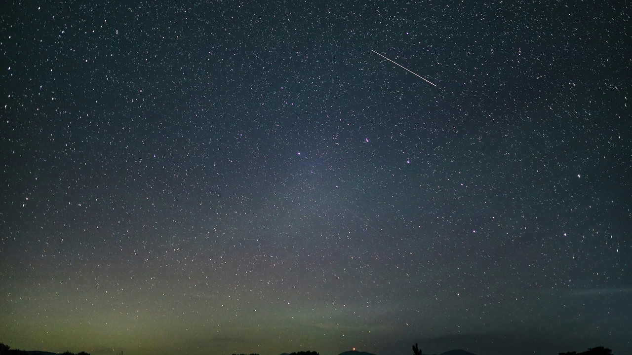 Perseids and Geminids meteor showers over a dark landscape with fireballs and streaks of light