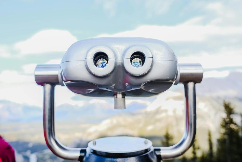 Coin operated binoculars overlooking a scenic mountain landscape, perfect for tourist attractions.