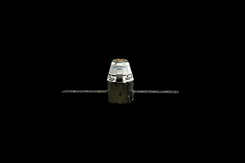 A SpaceX Dragon capsule orbited against the dark vastness of outer space.