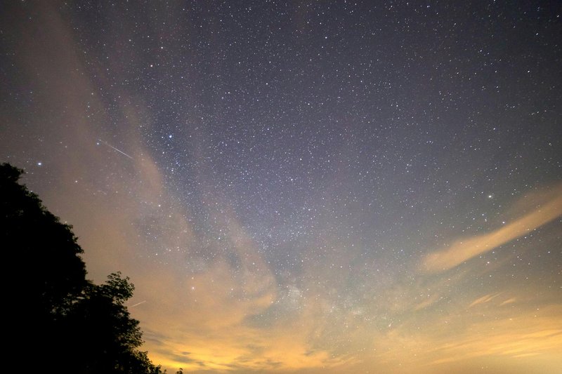 A breathtaking view of the star-filled night sky featuring the Milky Way and a meteor streak.