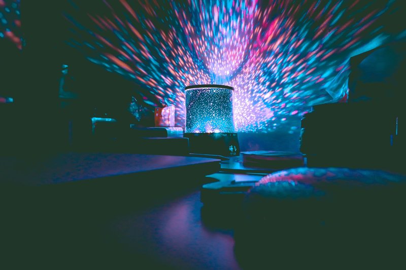 A colorful galaxy projector casting vibrant lights in a dark room. Perfect for setting a calm ambiance.