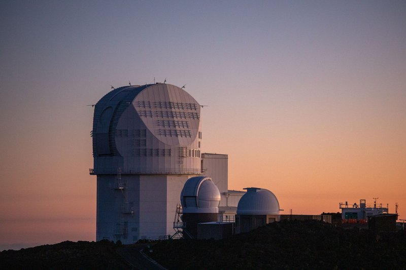 Modern solar observatory under a colorful sunset sky, showcasing architectural elegance against a serene backdrop.