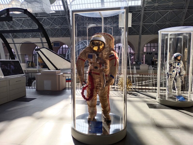 Historic space suits showcased in a museum with ample natural light.