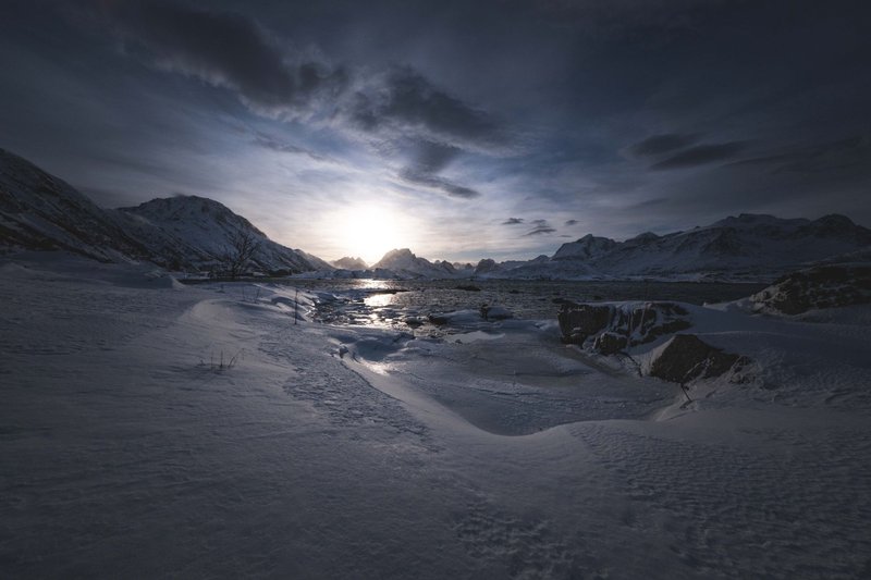 Captivating view of a serene snowy landscape with a breathtaking Arctic sunset captured in winter.