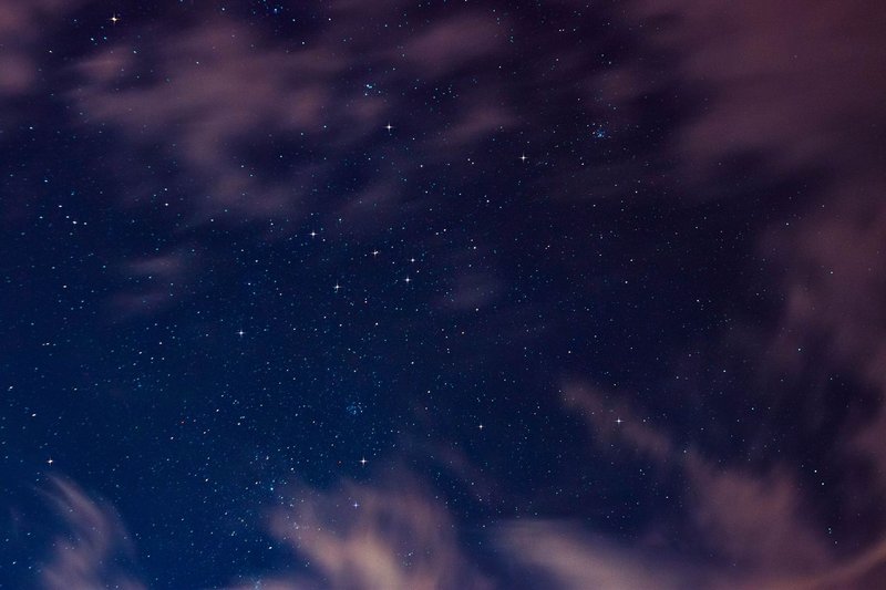 Beautiful starry night sky with scattered clouds and visible constellations.