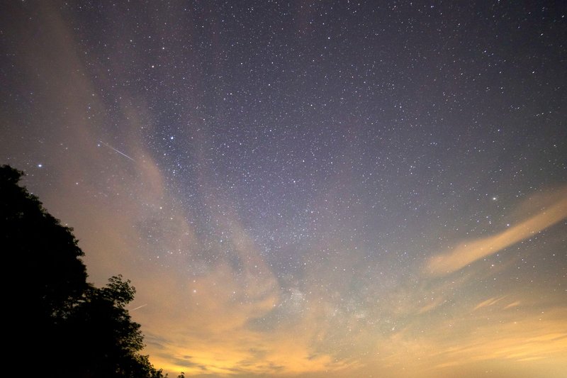 A breathtaking view of the star-filled night sky featuring the Milky Way and a meteor streak.