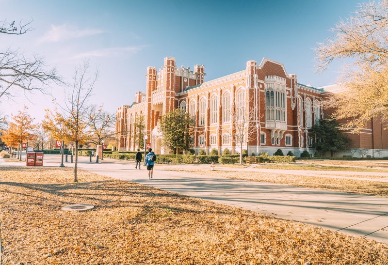 A scenic view of a historic university building surrounded by autumn foliage, reflecting academic architecture.