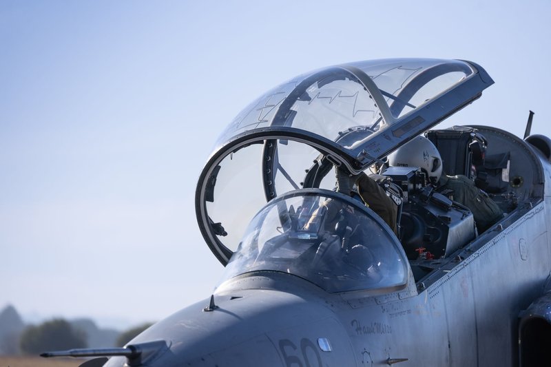 Detailed view of a military jet cockpit with pilots preparing for flight against a clear sky.