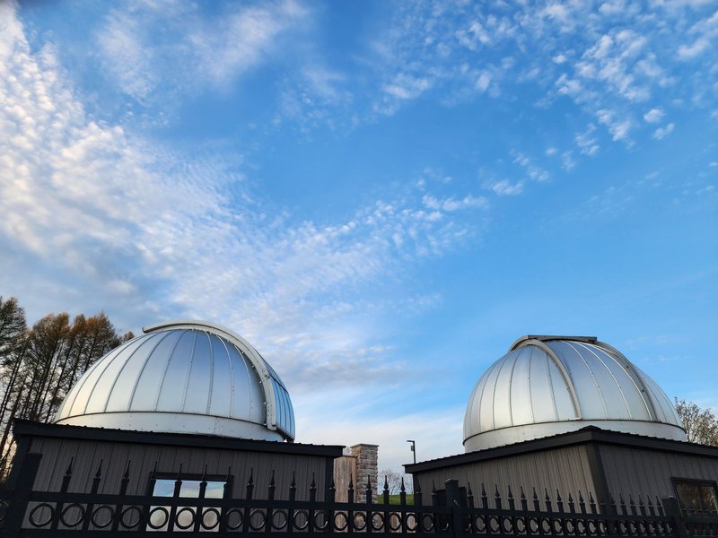 Two modern observatory domes under a blue sky, showcasing scientific exploration.