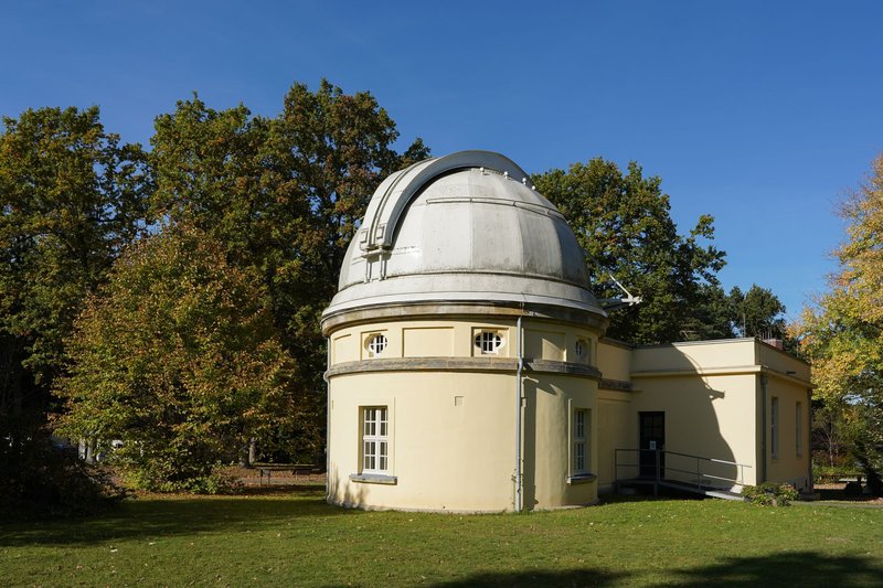 Historic astronomical observatory surrounded by lush greenery in Hamburg, Germany.